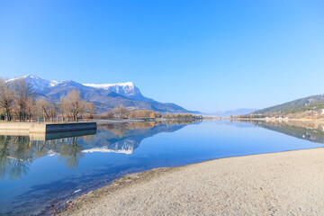 A scenics view of the Embrun, France lake with snowy mountains range in the background under a majestic blue sky