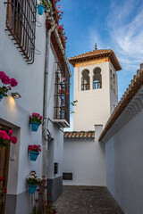 Narrow street in the town, flowered patio with tower view, Granada, Andalusia, Spain