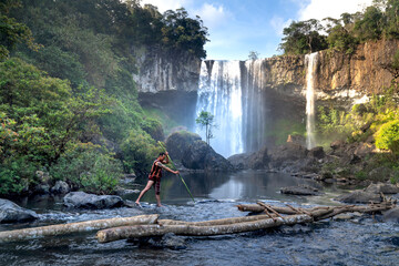 An ethnic minority man hunts fish in the stream with a spear in his hand at K50 Waterfall, K' Bang...