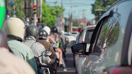 Bali, Indonesia. Motorcycles, scooters and a car stand on the road waiting for the traffic light to turn on.