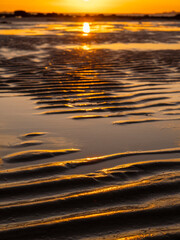 Sandy beach texture at sunset. Warm orange color. Nature scene at dusk. Summer time mood and atmosphere. Calm scenery.