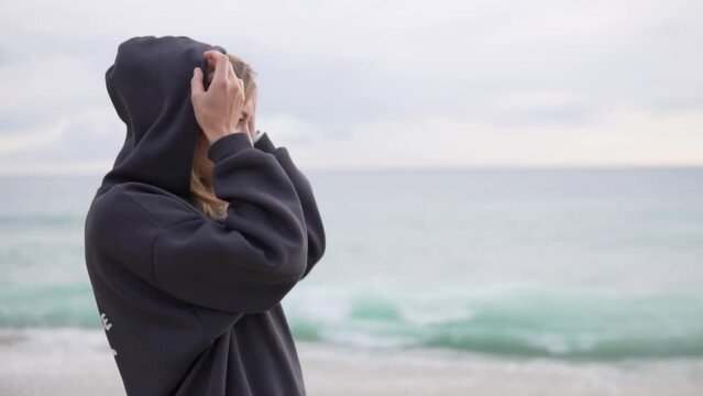 A beautiful woman removes the hood with a voice you are standing by the sea