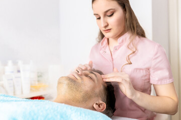 Fototapeta premium Beautician doing face treatment in beauty salon to a man.