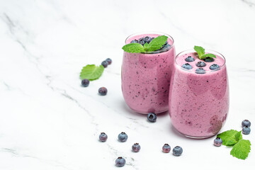 two glasses of fresh berries with yogurt smoothies fresh blueberries or bilberry on a light background. Long banner format. top view