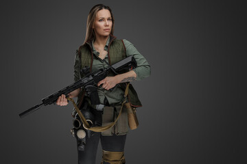 Studio shot of professional killer woman with rifle in setting of post apocalypse.