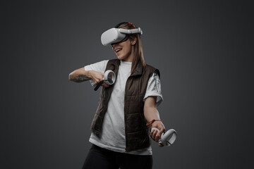 Studio shot of woman dressed in casual clothing posing with virtual reality goggles.