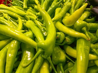Fresh green pepper in wooden basket at traditional grocery counter, fresh and healthy food idea, organic vegetable, many green peppers, local greengrocer concept
