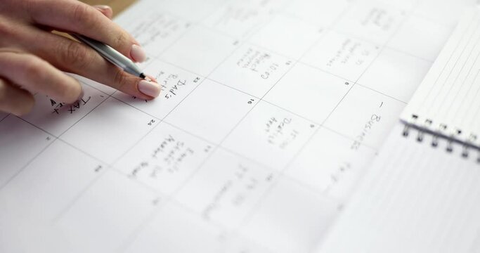 Women's hands fill the paper calendar, close-up