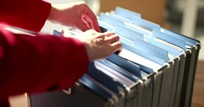 Hands sort through documents in a folder, close-up