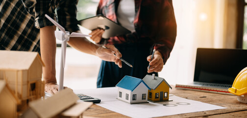 Two colleagues discussing data working and tablet, laptop with on on architectural project at construction site at desk in office