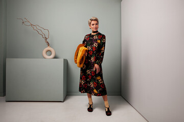 Senior fashion female model standing full length in studio wears black maxi floral dress and socks...