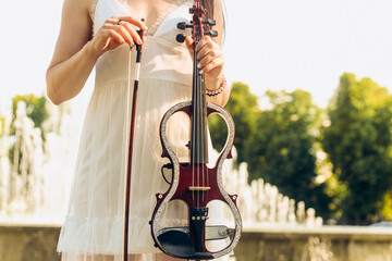 A fragment of an electric violin, a violin in the hands of a musician's girl