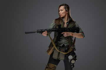 Fototapeta na wymiar Portrait of military woman with rifle looking to side isolated on grey background.
