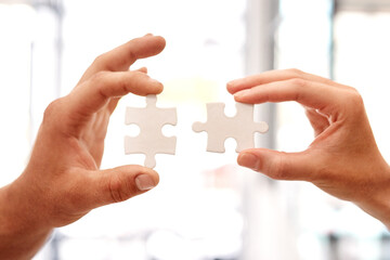 Putting the pieces of their big plan together. Closeup shot of two unrecognisable businesspeople holding puzzle pieces together.