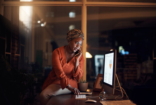 Ill Update The Details On My Side Too. A Young Businesswoman Talking On A Cellphone While Using A Computer In An Office At Night.