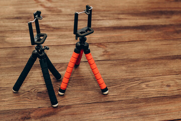 Two manual tripod monopods for a phone or a small camera on a wooden table.