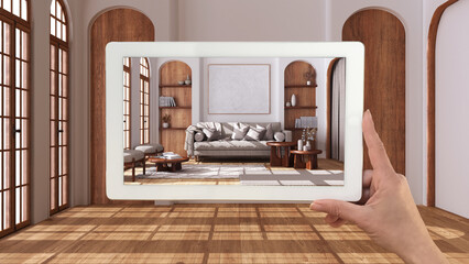 Augmented reality concept. Hand holding tablet with AR application used to simulate furniture and design products in empty interior with parquet floor, farmhouse living room