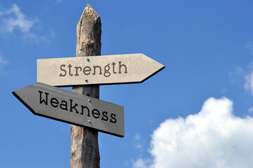 Strength and weakness - wooden signpost with two arrows, sky with clouds