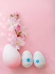 Obraz na płótnie Canvas Easter eggs and cherry flowers on a pink background with bokeh and copy space. Vertical photo