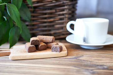 Chocolates on a cutting board, on the kitchen table with a white tea pair.