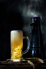 Large glass goblet with light beer against a dark wal