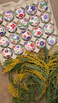Colorful Easter eggs and mimosa flowers rotation. Easter holiday concept. Easter egg is traditional symbol for religious holiday. Christian celebration traditions, flat lay top view slow motion