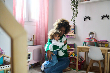 young black mother with fizzy hair and her little doughtier playing with educational toys in her room