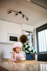 young black mother with fizzy hair and her little doughtier cooking in a big bright kitchen