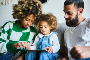 young interracial family with a black mother with fizzy hair spending time together at their sofa