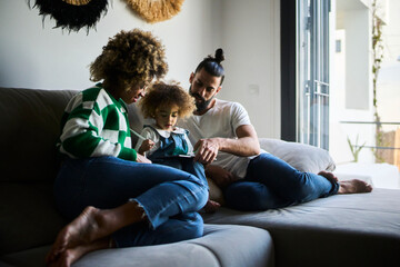 young interracial family with a black mother with fizzy hair spending time together at their sofa