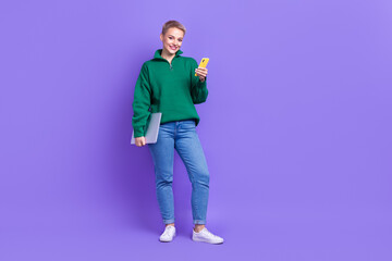 Full length photo of cute pretty lady wear green sweater texting modern device empty space isolated violet color background