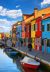 Burano island in Venice Italy. Picturesque old village over canal with boats among antique colourful houses and stone streets. Fishing town