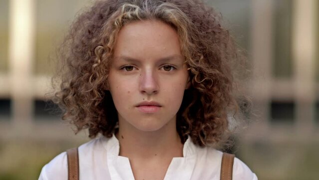 Portrait of a curly teenage girl with a serious expression.