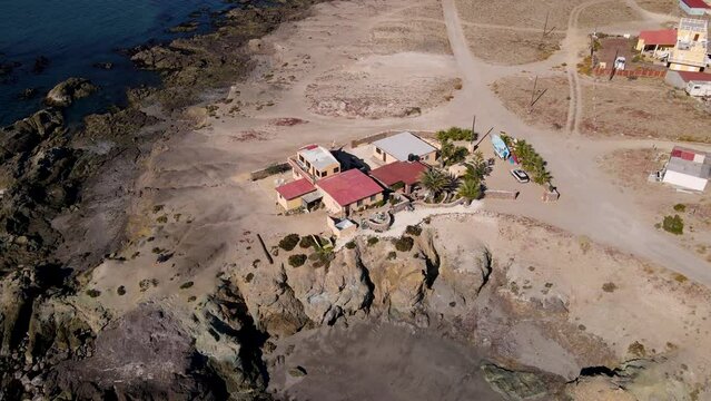 Aerial slow orbit around Mexican coastal villa house on top of sea cliff