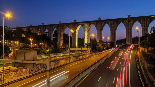 Time-lapse of highway traffic near Campolide station with Aguas Livres Aqueduct in background in the evening with car lights trails. Lisbon, Portugal