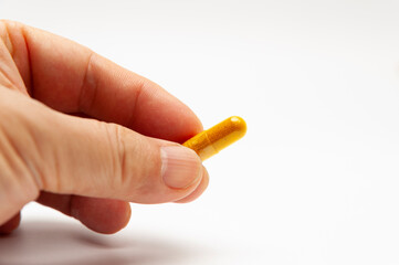 Man hand holding Turmeric supplement capsule isolated on white background with copy space