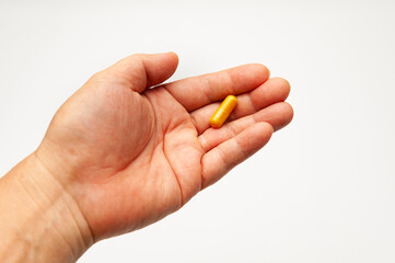 Turmeric supplement capsule in man hand isolated on white background with copy space.