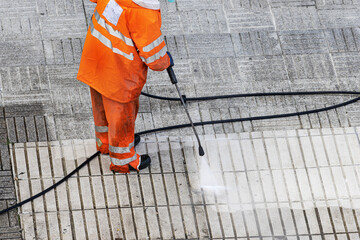 Worker cleaning a street sidewalk with high pressure water jet. Copy space