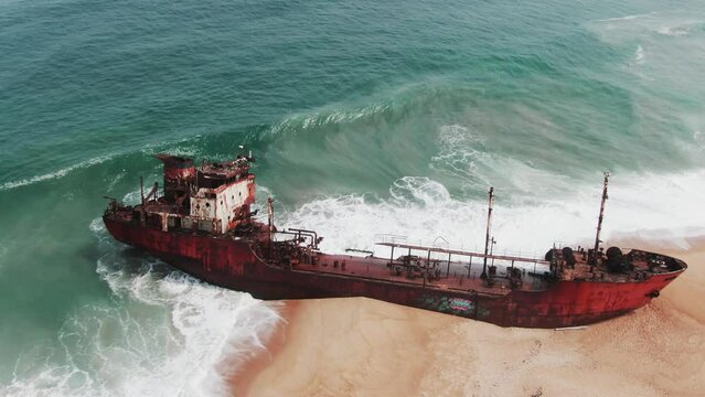 waves crashing into an old and rusty shipwreck on a beautiful beach in West Africa, Liberia, Robertsport