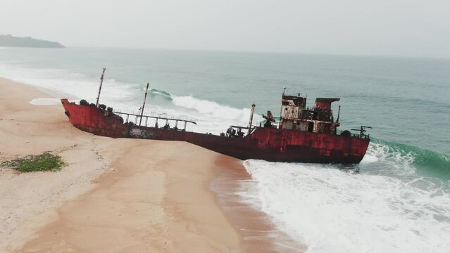 man running towards an abandoned shipwreck on the west african coast in Robertsport, Liberia