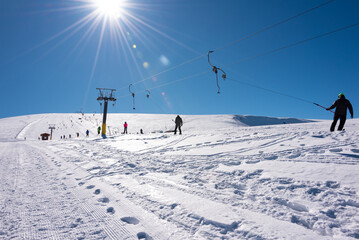 People using ski lift on sunny winter day on ski resort