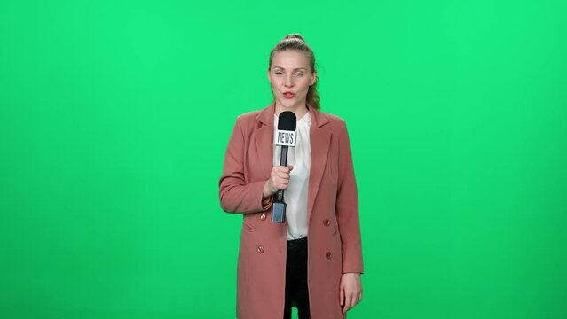 News, woman news reporter speaks into a microphone on a green background and looks into the camera, template for TV news agencies, woman journalist at work, chromakey.