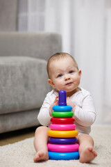 Cute baby girl playing with colorful toy pyramid