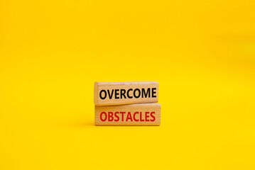 Overcome obstacles symbol. Concept words Overcome obstacles on wooden blocks. Beautiful yellow background. Business and Overcome obstacles concept. Copy space.