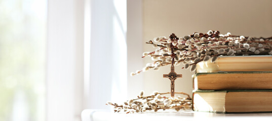 christian rosary cross, old biblical books, willow twigs on table, abstract light background....