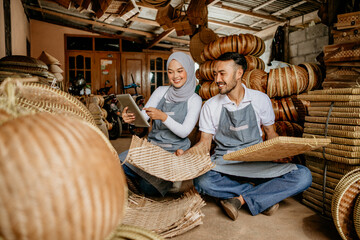 asian muslim woman and her partner checking bamboo product at their traditional warehouse