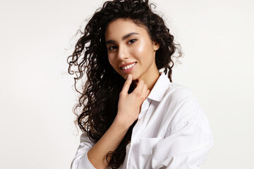 Young woman with curly black hair and clear glowing skin.