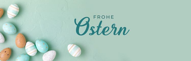 Happy Easter Greetings Banner -  German text.  Easter frame of pastel colored eggs on light green background. Panorama, banner, flay lay, top view with copy space.
