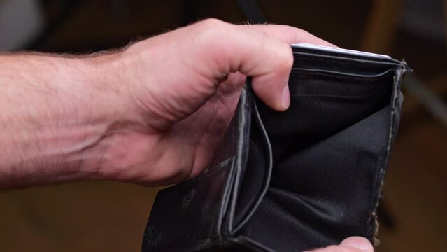 A man looks into an empty wallet. Inflation took all the money, unemployment in the labor market.