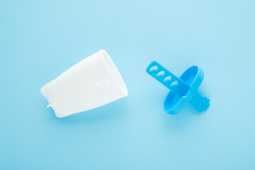 Opened white plastic container for homemade ice popsicles on stick. Light blue table background. Pastel color. Closeup. Cold sweet snack in summer. Top down view.